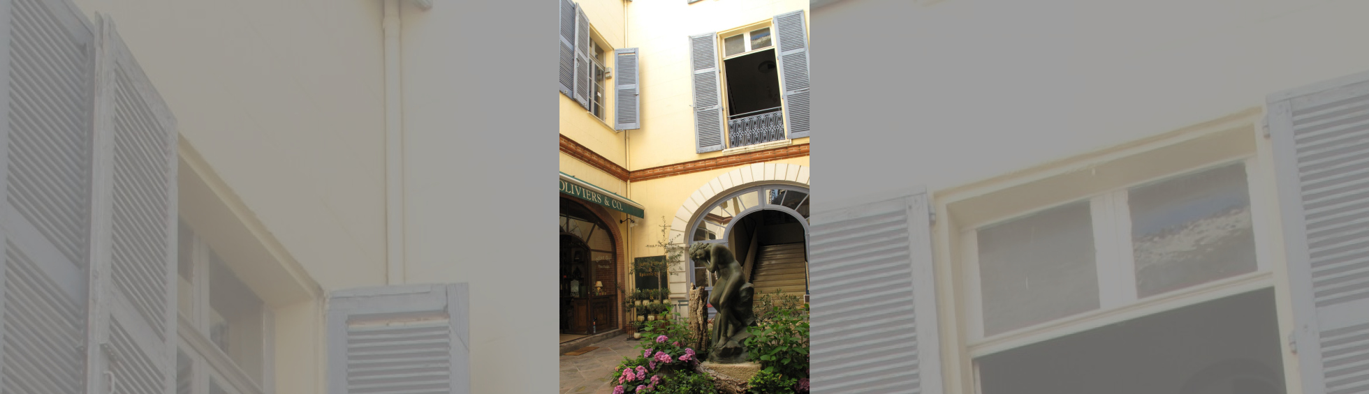 Le patio actuel desservant des commerces et le grand escalier,  au centre une statue représentant une baigneuse